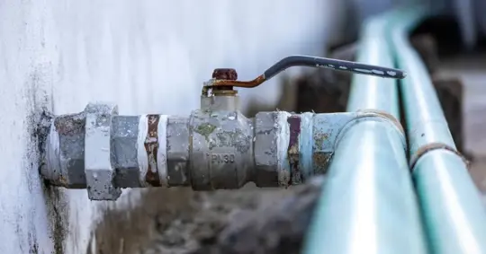 Close-up of plumbing pipe and valve on house rooftop